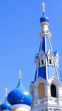 Güneşli bir günde açık mavi gökyüzü karşısında mavi kubbeleri olan kilise. Mavi gökyüzüne karşı kilisenin kubbesinde Ortodoks haçı.