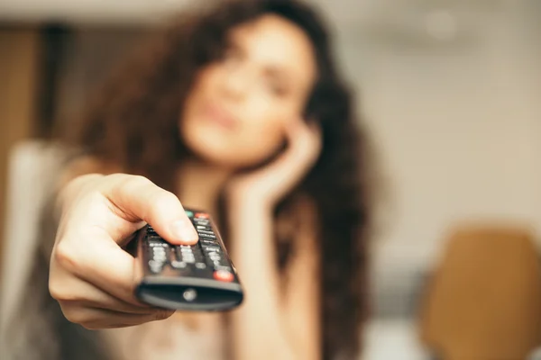 Meisje met een Tv remote afstandsbediening,, het kanaal wijzigen. — Stockfoto