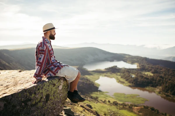 Hombre sentado en una roca mirando — Foto de Stock