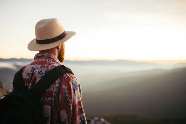 Człowiek z kapelusz i torebka, patrząc na zachód słońca — Zdjęcie stockowe