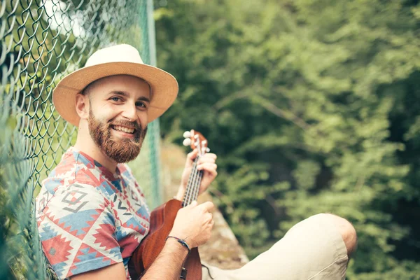 Homem tocando ukulele na natureza Imagens De Bancos De Imagens
