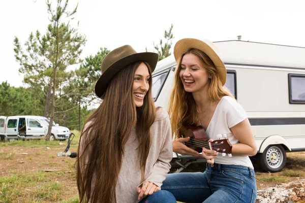 Two young and beautiful girls having fun playing ukulele with a — Stock Photo, Image