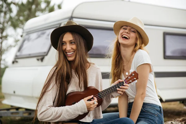 Dos chicas sonriendo apoyadas en una furgoneta . Fotos de stock libres de derechos