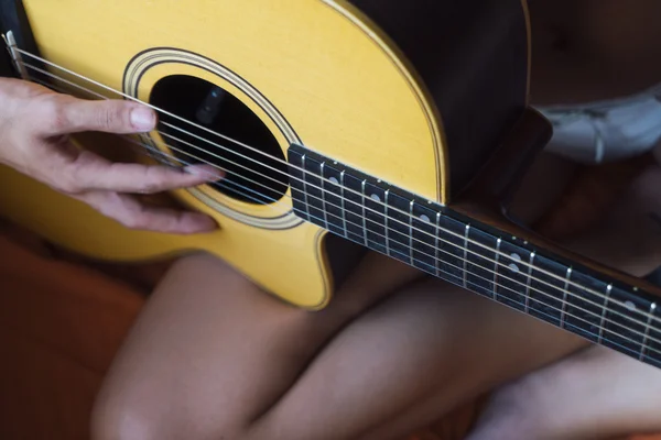Жінка сидить на ліжку і грає на гітарі — стокове фото