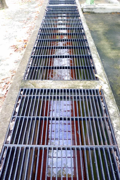 Middle point focus of steel drain water flows down through the steel manhole cover on a sunlight afternoon. — Stock Photo, Image