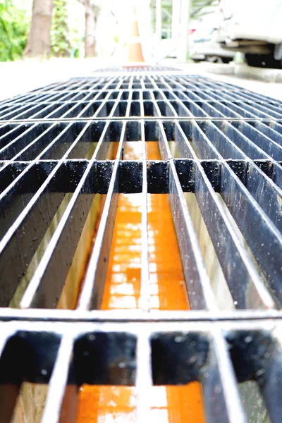 Middle point focus of steel drain water flows down through the steel manhole cover on a sunlight afternoon. — Stock Photo, Image