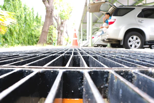 El foco del punto medio del agua de drenaje de acero fluye hacia abajo a través de la tapa de la alcantarilla de acero en una tarde de luz solar . —  Fotos de Stock