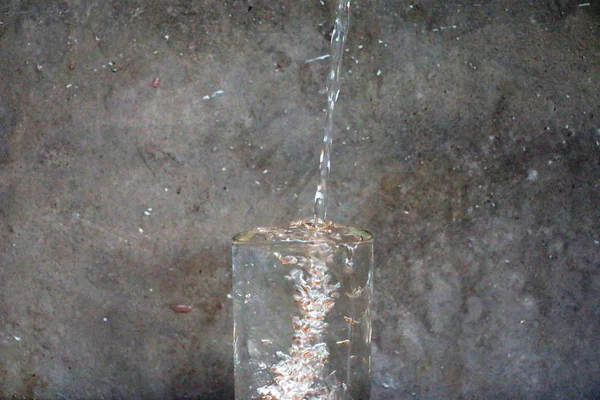 Virkningen av dråpevann og vannglass på trebordet foran sementveggens bakgrunn – stockfoto