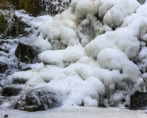 Beautiful frozen waterfall in the winter. Frozen water an ice everywhere. Amazing ice formations. Rocks surrounding the water