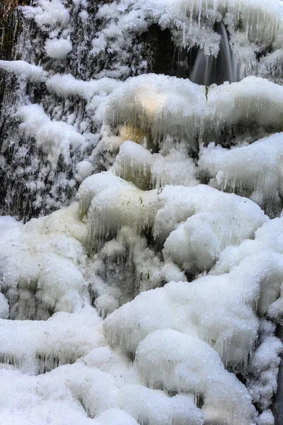 冬の美しい凍結滝 凍った水はどこでも氷です 素晴らしい氷の形成 森の中を光が照らす — ストック写真