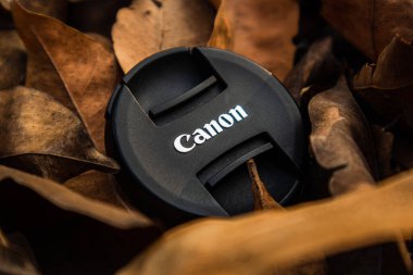 bogor,indonesia - 07 july 2021 : canon lens cap on a pile of dry leaves in the morning sunlight