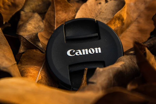bogor,indonesia - 07 july 2021 : canon lens cap on a pile of dry leaves in the morning sunlight