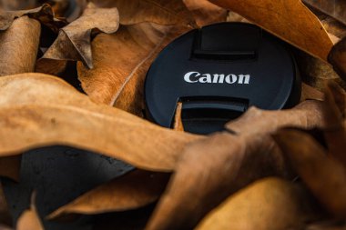 bogor,indonesia - 07 july 2021 : canon lens cap on a pile of dry leaves in the morning sunlight