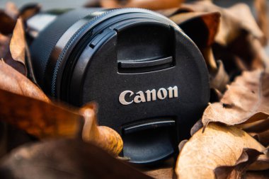 bogor,indonesia - 07 july 2021 : canon lens on a pile of dry leaves with morning light