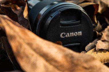 bogor,indonesia - 07 july 2021 : canon lens on a pile of dry leaves with morning light