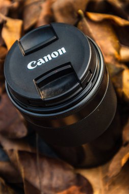 bogor,indonesia - 07 july 2021 : canon lens on a pile of dry leaves with morning light