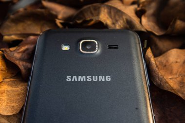 bogor,indonesia - 07 july 2021 : samsung mobile on a pile of dry leaves with morning light