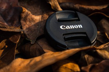 bogor,indonesia - 07 july 2021 : canon lens cap on a pile of dry leaves in the morning sunlight