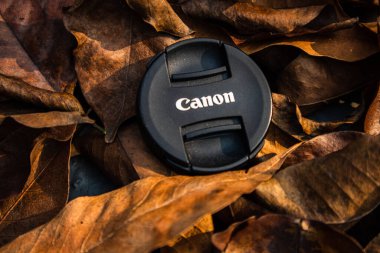 bogor,indonesia - 07 july 2021 : canon lens cap on a pile of dry leaves in the morning sunlight
