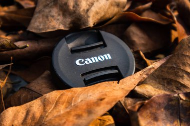bogor,indonesia - 07 july 2021 : canon lens cap on a pile of dry leaves in the morning sunlight