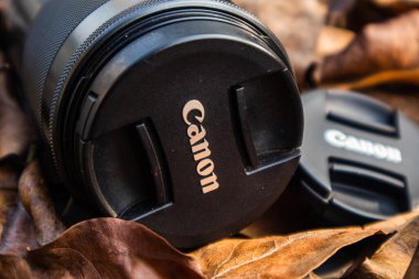bogor,indonesia - 07 july 2021 : canon lens on a pile of dry leaves with morning light