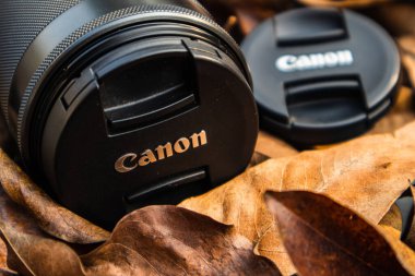bogor,indonesia - 07 july 2021 : canon lens on a pile of dry leaves with morning light