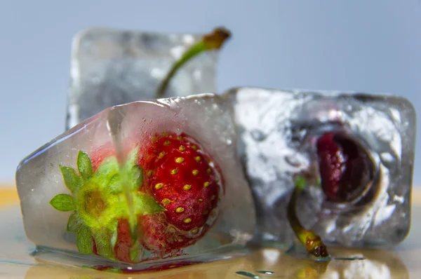 Dondurulmuş vişne ve çilek bir ahşap yüzeyde buz kalıbı