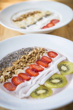 Çilekli meyve suyu kasesi, hindistan cevizi, kivi, granola ve chia tohumlu.