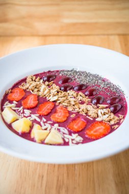 Meyve suyu kasesi, karışık yoğurt, ananas, üzüm, çilek, chia tohumu ve badem gevreği.