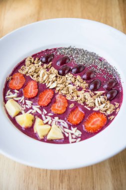 Meyve suyu kasesi, karışık yoğurt, ananas, üzüm, çilek, chia tohumu ve badem gevreği.