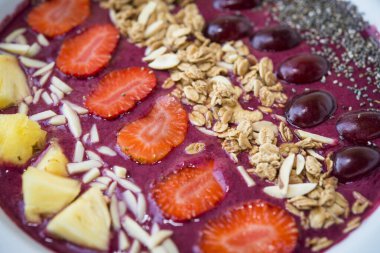 Meyve suyu kasesini böğürtlenli yoğurt, ananas, üzüm, çilek, chia tohumu ve badem gevreğiyle kapat.
