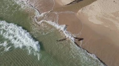 Turkuaz deniz dalgalarının kumlu sahil şeridinde dalgalandığı güzel görüntüler.