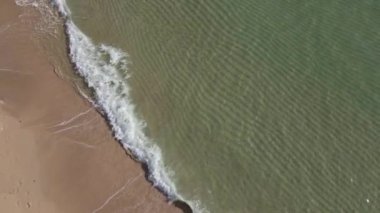 Turkuaz deniz dalgalarının kumlu sahil şeridinde dalgalandığı güzel görüntüler.