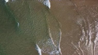 Turkuaz deniz dalgalarının kumlu sahil şeridinde dalgalandığı güzel görüntüler.