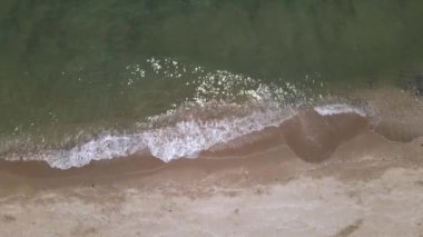 Turkuaz deniz dalgalarının kumlu sahil şeridinde dalgalandığı güzel görüntüler.