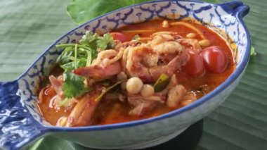 Bir kase Thai, Tom Yam deniz ürünleri çorbası kameranın önünde dönüyor.