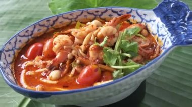 Bir kase Thai, Tom Yam deniz ürünleri çorbası kameranın önünde dönüyor.