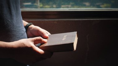 Kutsal İncil, İncil 'i elinde tutan genç adam Tanrı inancı, maneviyat ve din kavramı ile ilişki kurmak için dua etmeye hazır..