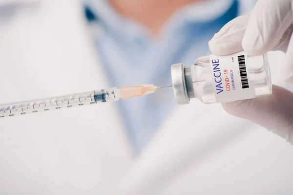 Covid-19 Corona virüsüne karşı yapılan kavramsal mücadele, laboratuvarda bulunan doktor ya da bilim adamı çocuk ya da daha yaşlı yetişkinler için sıvı aşı içeren bir şırınga taşıyor, kavram: hastalıklar, tıbbi bakım, bilim.