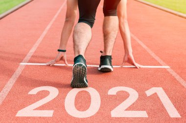 Spor üniformalı adamlar etrafta koşuşturuyor. Sağlıklı bir yaşam tarzı ve aşılanmış bir vücut. Spor ayakkabıları yakın plan, 2020 'de bitir. Yeni yıla başla 2021 planları, hedefleri, hedefleri