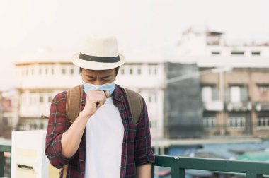 Öksüren bir adam. Şehirdeki hava kirliliği yüzünden maske takan bir adam. Başbakan 2.5 toz ve Coronavirus hastalığını korumak için N95 maskesi takın (COVID-19)