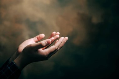 Tanrı 'ya inançla ve inançla dua eden eller, arka planda. Umudun, sevginin ve bağlılığın gücü.