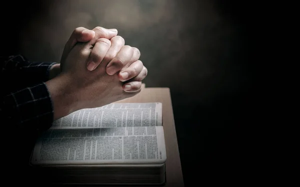 Christian life crisis prayer to god. Man Pray for god blessing to wishing have a better life. man hands praying to god with the bible. believe in goodness. Holding hands in prayer on a wooden table.