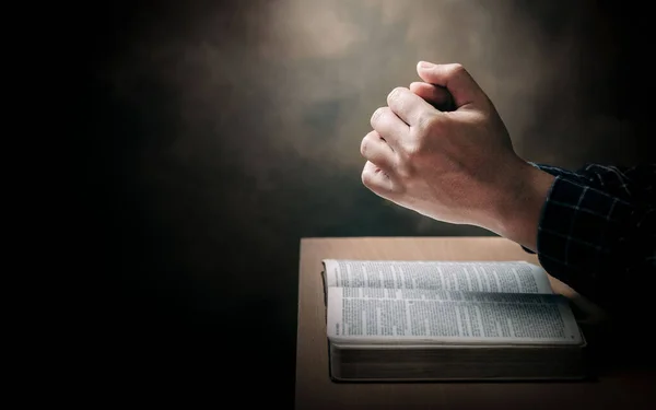 Christian life crisis prayer to god. Man Pray for god blessing to wishing have a better life. man hands praying to god with the bible. believe in goodness. Holding hands in prayer on a wooden table.
