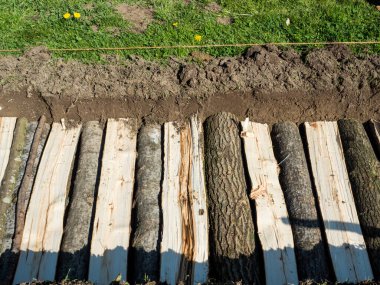 Permakültür hendek kenarı yeşil çimenli yarım uzun odun kütükleri