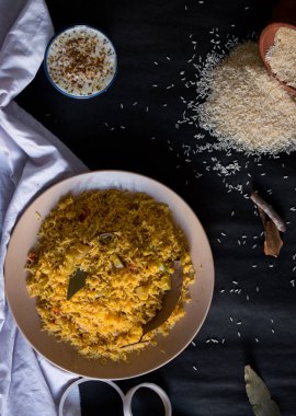 Siyah arka planda bazı malzemelerle birlikte bir tabakta baharatlı pirinç pişirdim. Sıcak baharatlar, çiğ pirinç pilav, kaymak. Sağlıklı tarif, üst görünüm