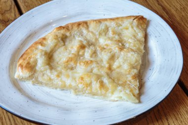 Peynirli büyük bir dilim pizza. Peynirli sıcak tortilla, Khachapuri, Kafkas mutfağı.