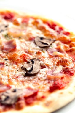 Beyaz tabakta kısmi jambon ve mantarlı pizza.