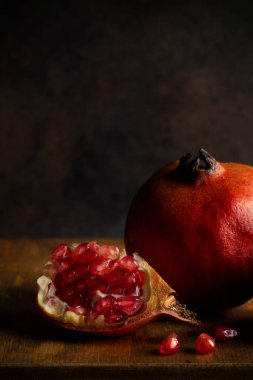 Çeyrek bir nar, koyu tonlu bir nar parçasının kısmi görüntüsü önünde.