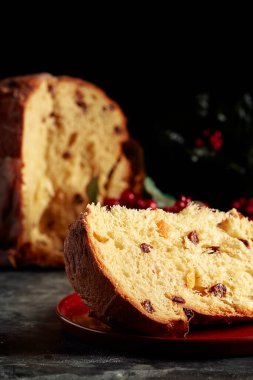 Kırmızı tabakta noel panettone 'u. Arka planda Noel ekmeği ve ökseotu var. Koyu arkaplan